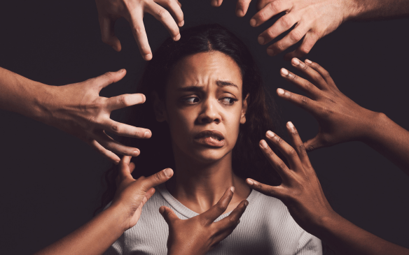 Mulher cercada por mãos, representando ansiedade e pressão emocional.